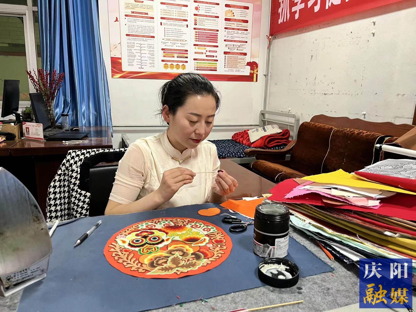 李慶英正在創(chuàng)作布貼畫作品。